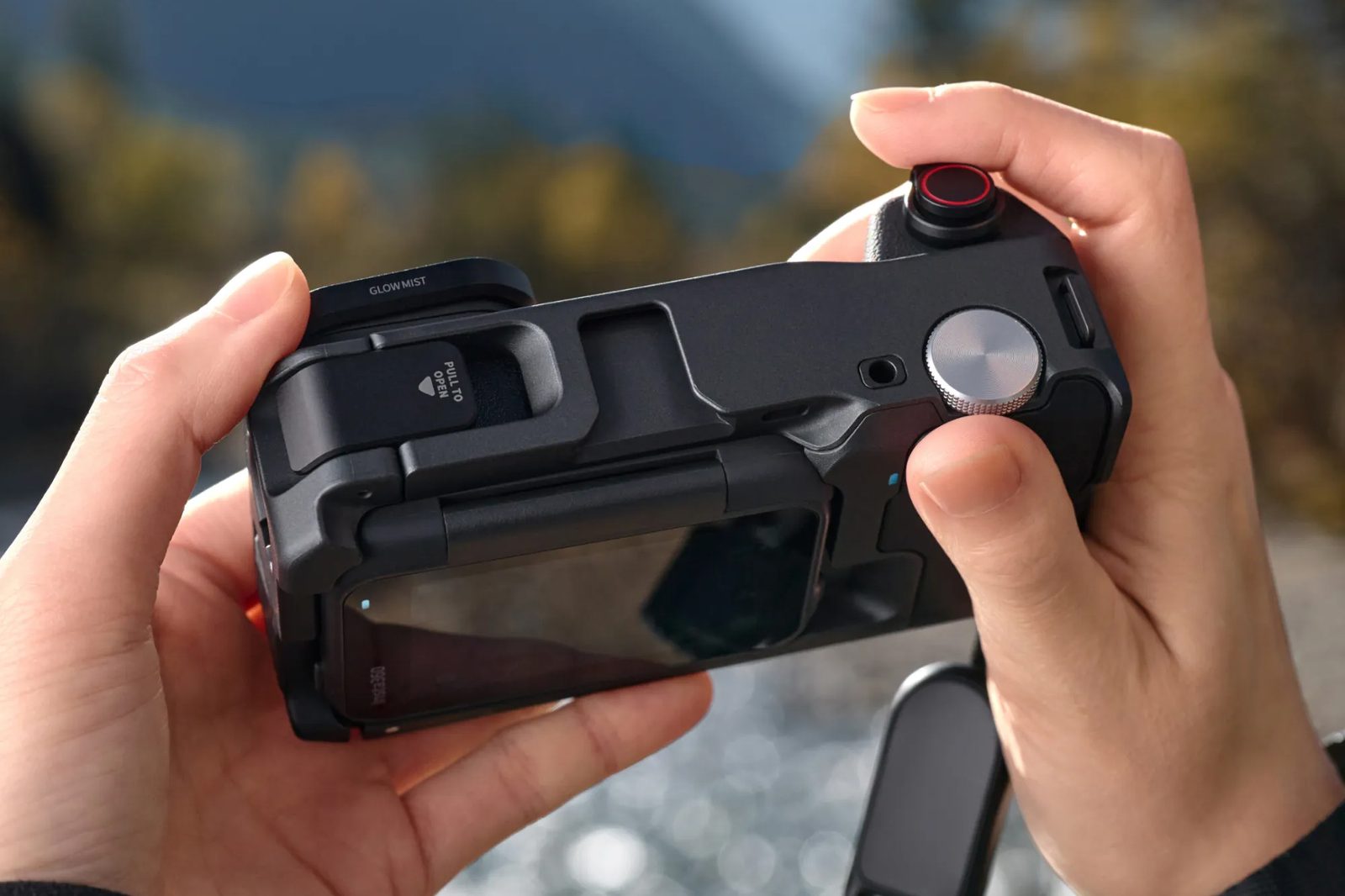 Hands holding the Ace Pro 2 with the Glow Mist filter by a mountain river