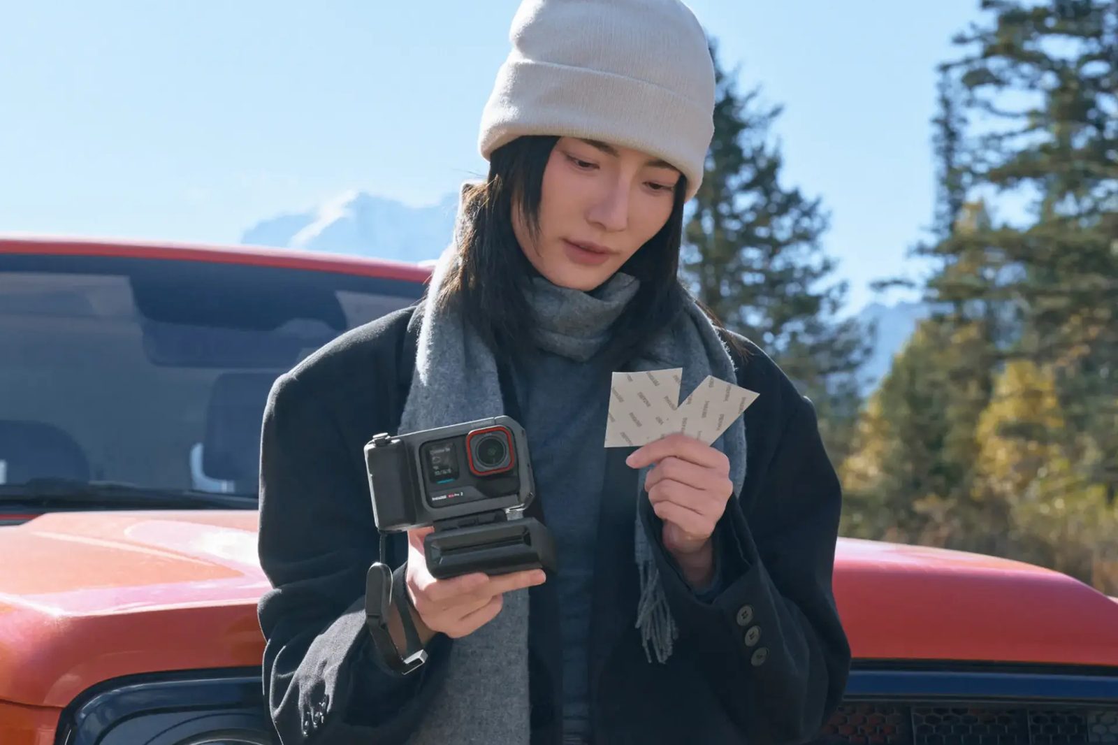 Woman holding instant prints from the Ace Pro 2 printer beside an orange truck